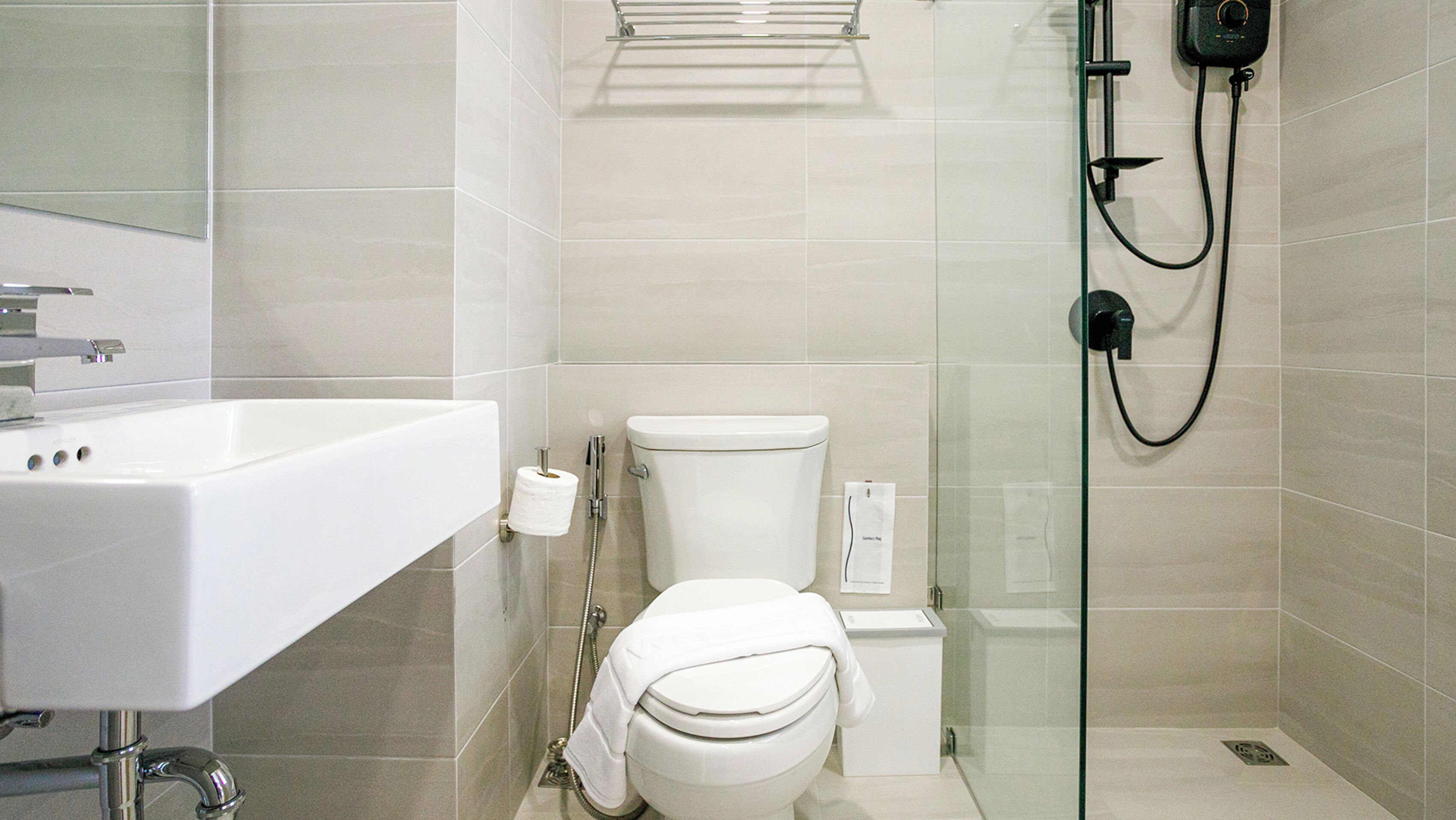 A modern bathroom with a toilet, sink, and glass shower enclosure.