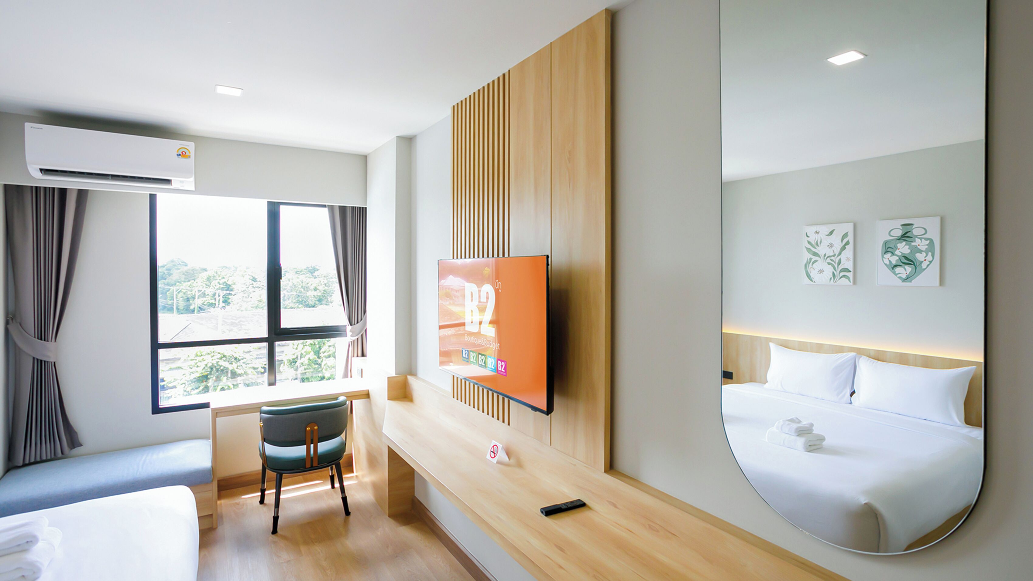 Una habitación de hotel con cama, escritorio con silla, televisión y un ventanal con cortinas.