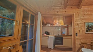 Een houten hut van binnen, met een keuken, een eethoek en een zithoek.