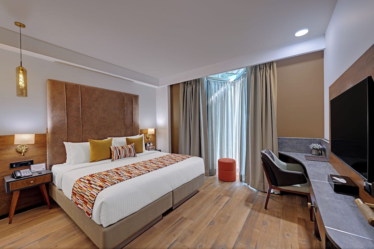 Una habitación de hotel moderna con una cama grande, un escritorio y un televisor.