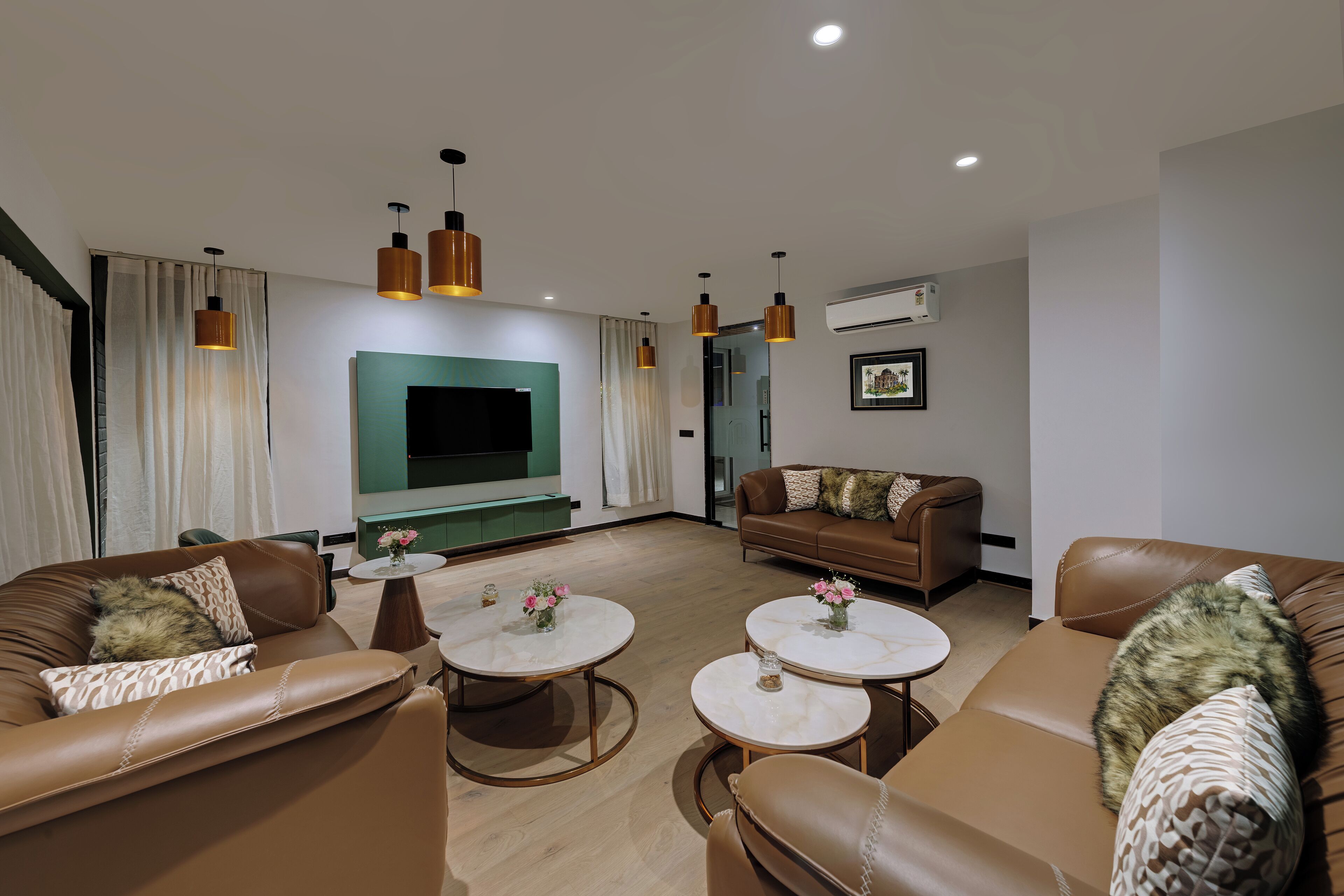 A modern living room with leather sofas, round coffee tables, and pendant lighting.