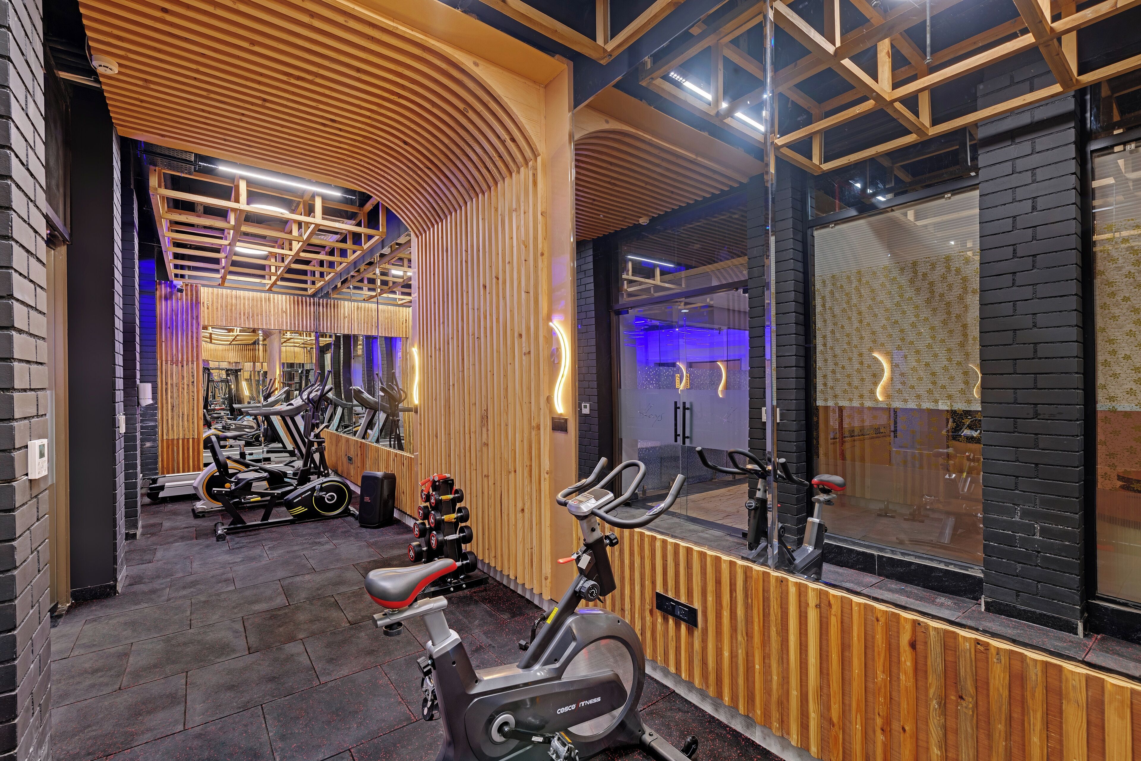 A gym with exercise equipment, wooden paneling, and a large mirror.