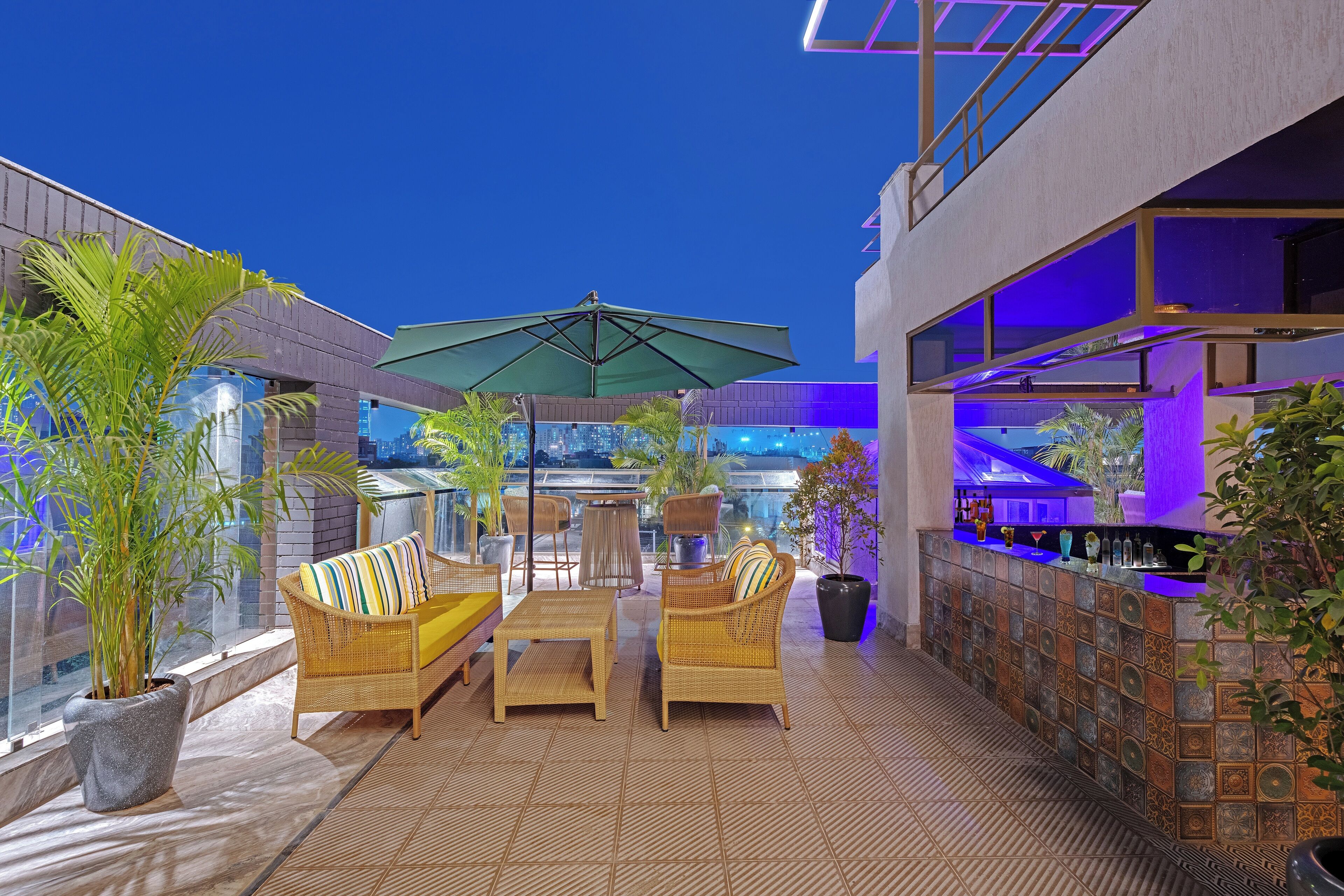 An outdoor seating area with wicker furniture, a bar, and potted plants.