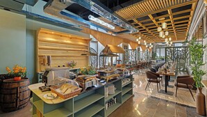 Een buffetopstelling met diverse gerechten en een zithoek met tafels en stoelen.