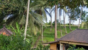 A traditional building with a tiled roof, surrounded by lush greenery and palm trees. - Pondok Hari Baik (Selemadeg)