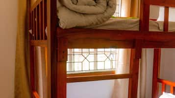 A bunk bed with a window, curtains, and a woven basket.