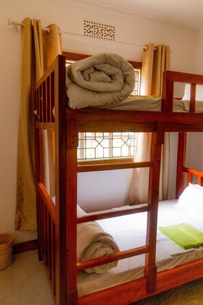 Una litera con ventana, cortinas y una cesta tejida.