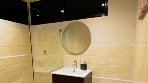 A bathroom with a glass shower enclosure, a sink with a mirror, and a toilet.