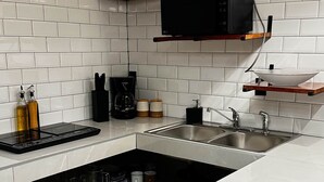 A modern kitchen with white subway tiles, a black microwave, a blender, and a coffee maker.