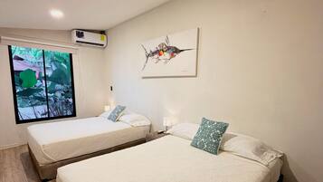 Een kamer met twee bedden, een raam met uitzicht, een airconditioning en een plafondlamp.