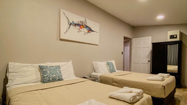 A hotel room with two beds, a ceiling light, and a door.
