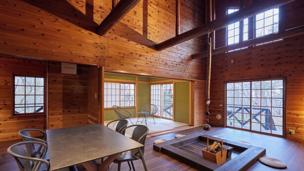 A wooden cabin interior with a dining table, chairs, a seating area with cushions, and large windows. - rinne 2nd living Nasu Garden (Nasu)