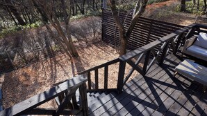 A wooden deck with a metal railing, surrounded by trees and a fence. - rinne 2nd living Nasu Garden (Nasu)