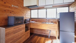 A compact kitchen with wooden cabinetry, a built-in microwave, a sink, and a refrigerator. - rinne 2nd living Nasu Garden (Nasu)