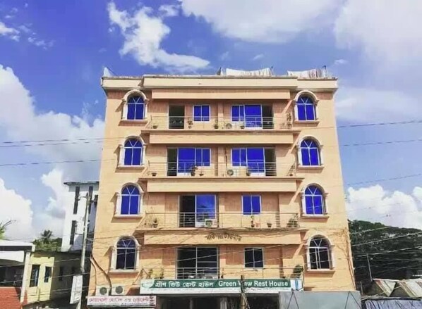 A multi-story building with a flat facade, multiple balconies, and a sign indicating it is a rest house.