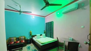 A bedroom with a bed, a desk, a chair, a ceiling fan, and an air conditioning unit. - Green View Rest House (Sreemangal)