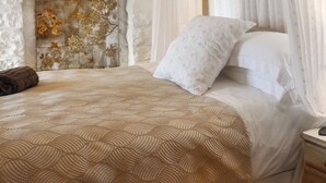 A bed with a patterned bedspread, a white pillow, and a brown towel on the side. - 1 bedroom accommodation in St Davids (St Davids)