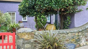 A stone wall with a potted plant and a sign reading "Snowdrop Cottage." - 1 bedroom accommodation in St Davids (St Davids)