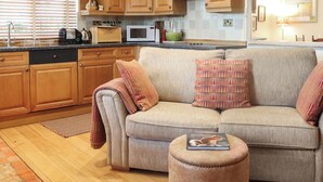 A cozy living room with wooden cabinets, a sofa, and a coffee table. - 1 bedroom accommodation in St Davids (St Davids)