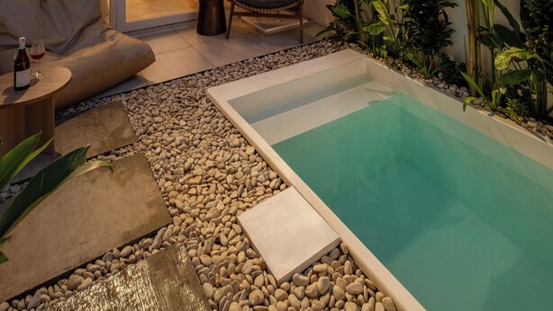 Una casa moderna con piscina, comedor y sala de estar con sofá y televisor.