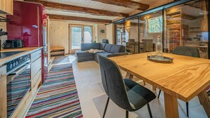 Una cocina moderna con un refrigerador rojo, una mesa de comedor de madera con sillas y una alfombra colorida a rayas.