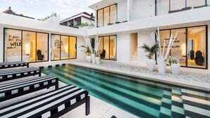 A modern hotel with a pool, outdoor seating, and large windows. - the den canggu (Canggu)