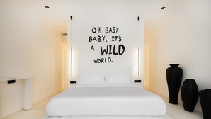 A modern bedroom with a large bed, a wall-mounted sign, and black vases. - the den canggu (Canggu)