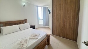 A bedroom with a wooden bed, a nightstand, a wardrobe, and a window with curtains.