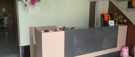 A reception desk with a fan, a framed picture, and a potted plant.