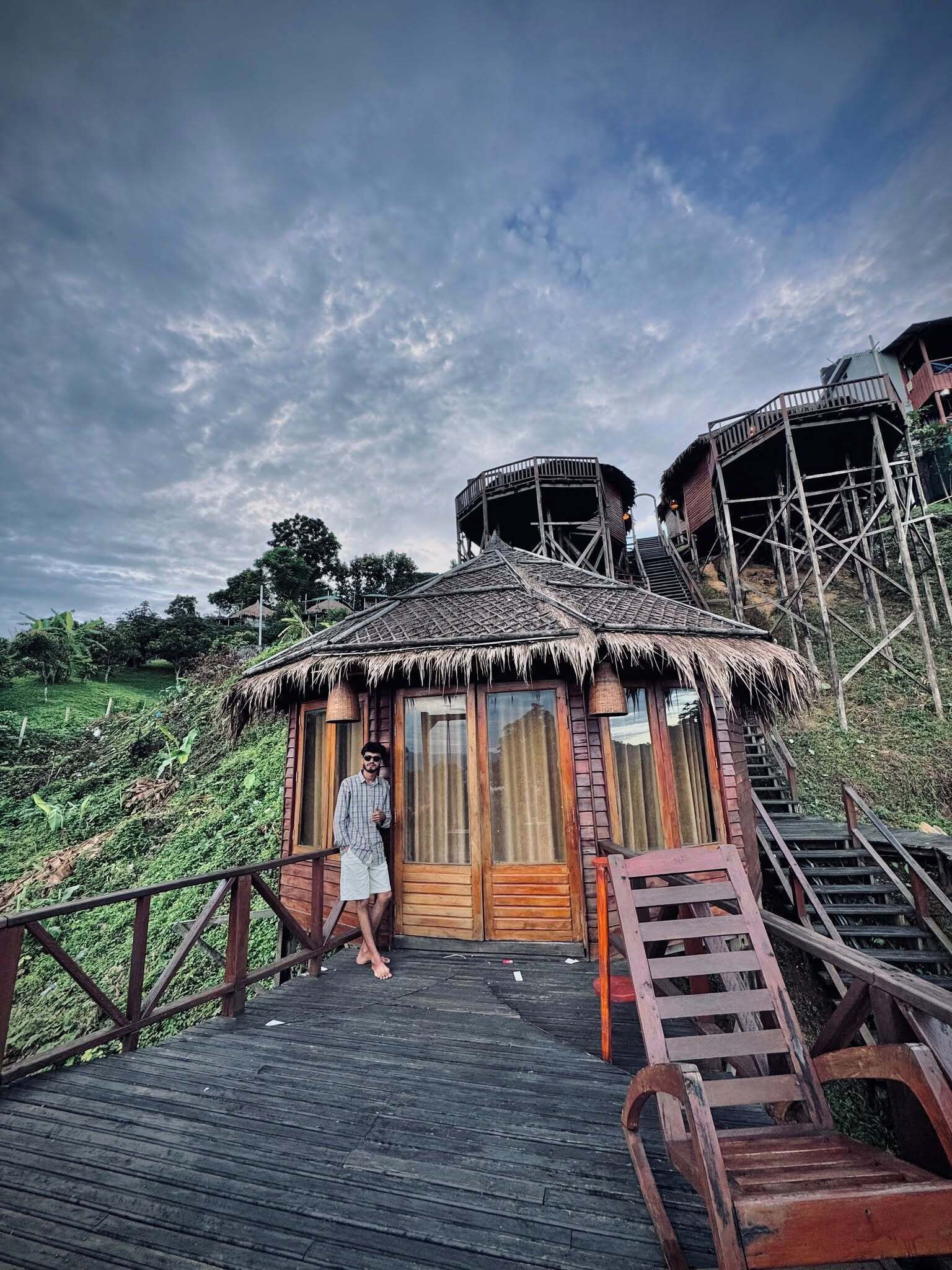 A wooden structure with a thatched roof, a wooden staircase, and a wooden deck.