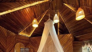 A circular bed with a canopy, wooden walls, and hanging lights. - Niribili Eco Resort (Sajek)