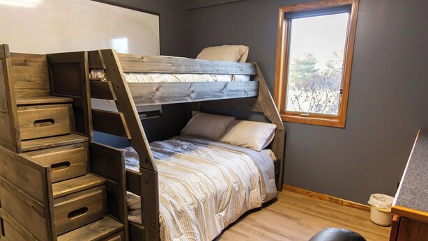 A bunk bed with storage drawers, a window, and a desk in a room with wooden flooring. - Peaceful Guest House Beside The Elks Golf Course – A Relaxing Country Getaway (Kearney)
