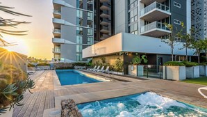Un hotel moderno con piscina en la azotea, sillones de descanso y vistas de los edificios circundantes.