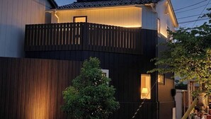 A two-story building with a balcony, wooden paneling, and a lamp visible through a window. - Kanazawaya Motogikucho (Kanazawa)