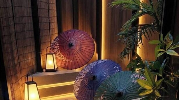 A serene outdoor area with a wooden deck, a table with decorative items, and a water feature. - Kanazawaya Motogikucho (Kanazawa)