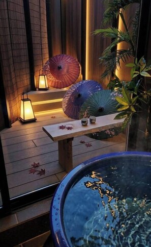 Un espace extérieur paisible, doté d’une terrasse en bois, d’une table agrémentée d’objets décoratifs et d’un élément aquatique.