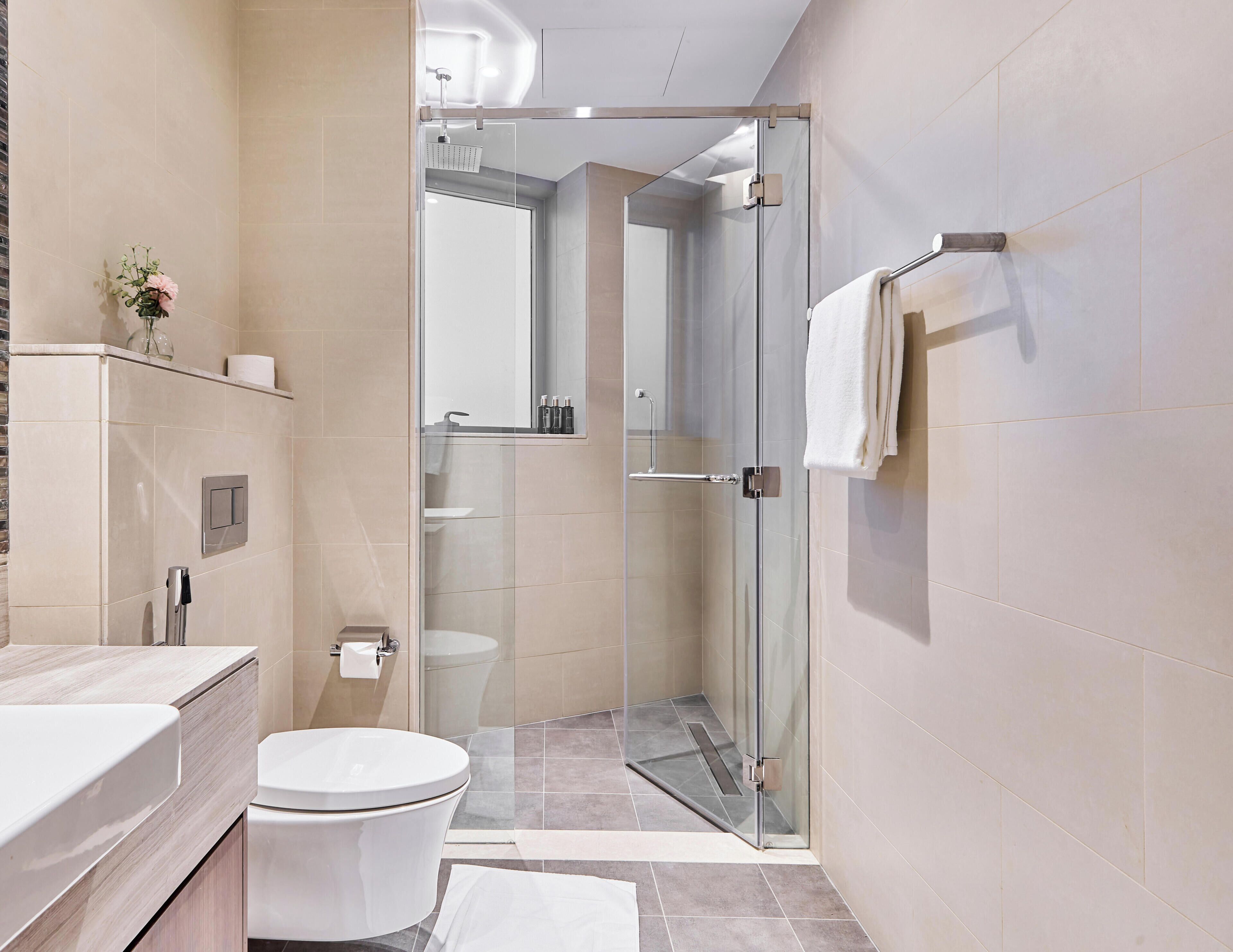 A modern bathroom with a glass shower enclosure, a toilet, and a vanity with a mirror.