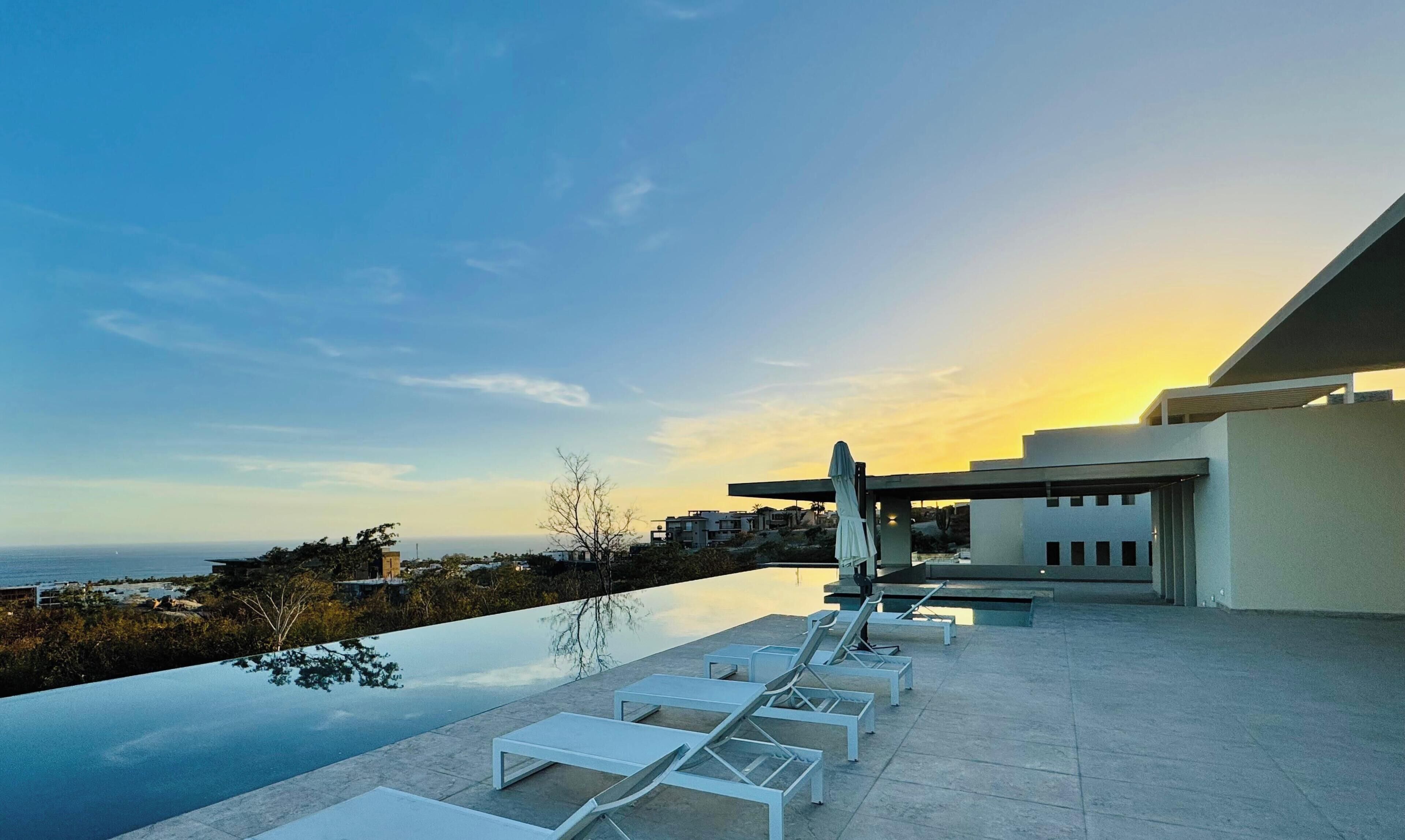 Una piscina al aire libre, sombrillas, sillones reclinables de piscina