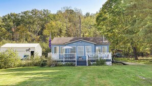 A blue house with a porch and a white shed in a grassy yard. - Todd Lake Home: Fish, Snowmobile & Golf! (Reed City)
