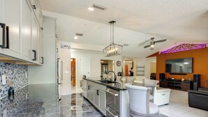 A modern kitchen with granite countertops, stainless steel appliances, and a central island with bar stools. - Backyard Oasis w/ Private Pool: Jacksonville Gem (Jacksonville)