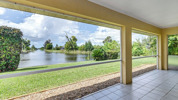 A spacious indoor area with large windows overlooking a pond and lush greenery. - Waterfront Cape Coral Home: Views & Birdwatching (Cape Coral)