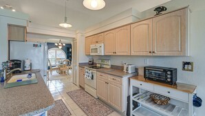 A modern kitchen with granite countertops, a built-in microwave, a toaster, and wooden cabinets. - Waterfront Cape Coral Home: Views & Birdwatching (Cape Coral)