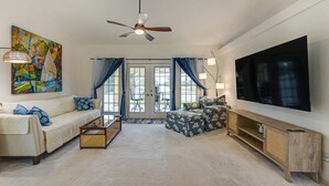 A spacious living room with a large flat-screen TV, a ceiling fan, and a painting on the wall. - Waterfront Cape Coral Home: Views & Birdwatching (Cape Coral)