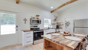 A modern kitchen with white cabinetry, a wooden dining table, and a built-in oven.