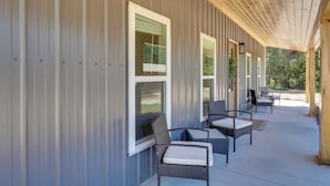 A covered outdoor seating area with wicker furniture and a wooden ceiling.