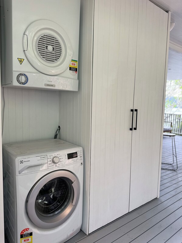 A laundry area with a front-loading washer and dryer, a white cabinet with a vent, and a sliding door closet.