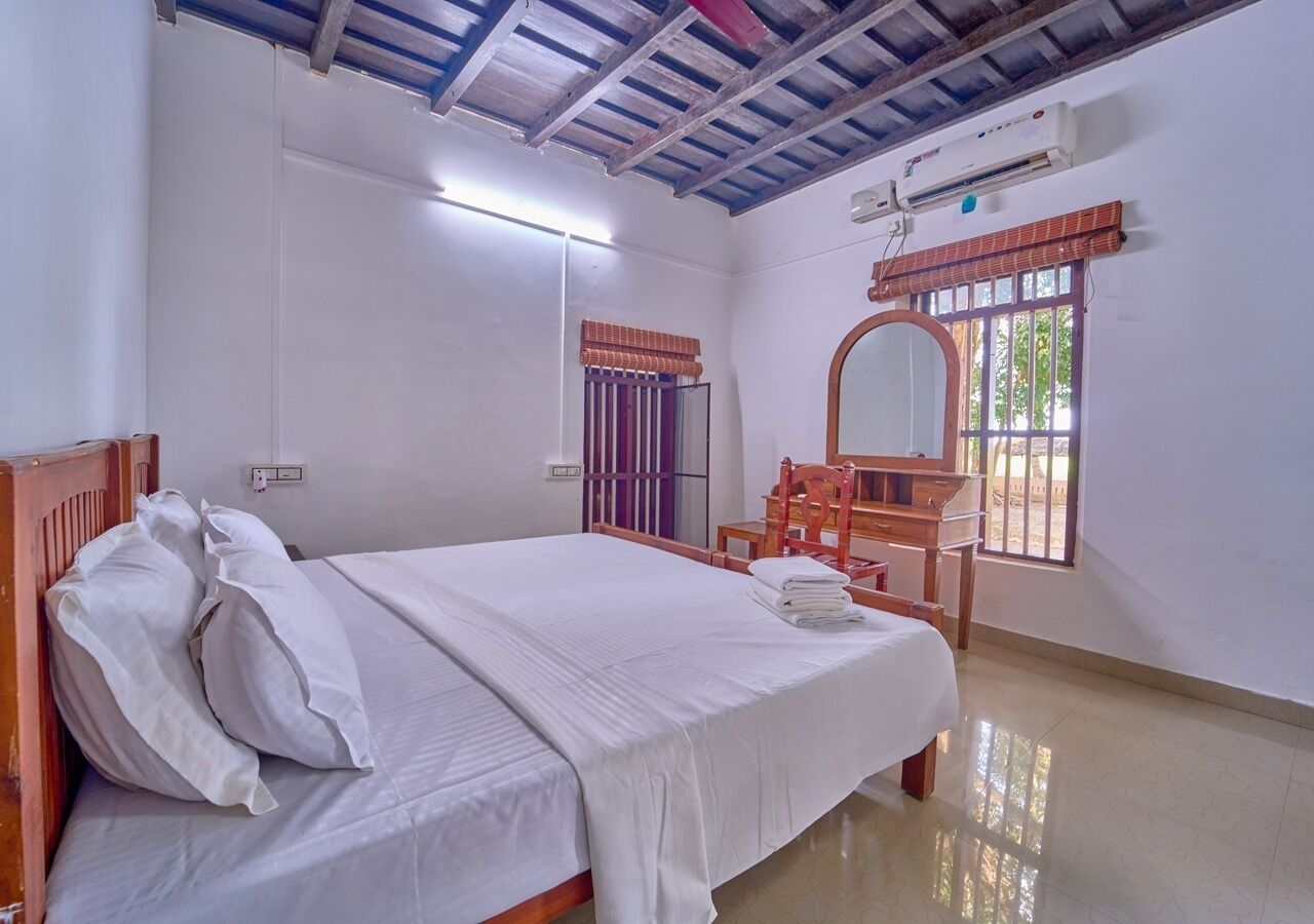 A room with a bed, a wooden chair, a window with a view, and a ceiling fan.