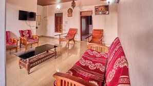 Una sala de estar con un sofá, sillas, una mesa de centro y un televisor.