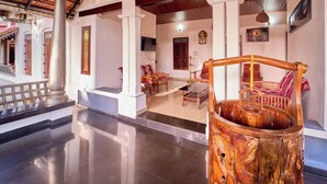 Un vestíbulo espacioso con piso pulido, una gran fuente de agua de madera y mobiliario tradicional de madera.