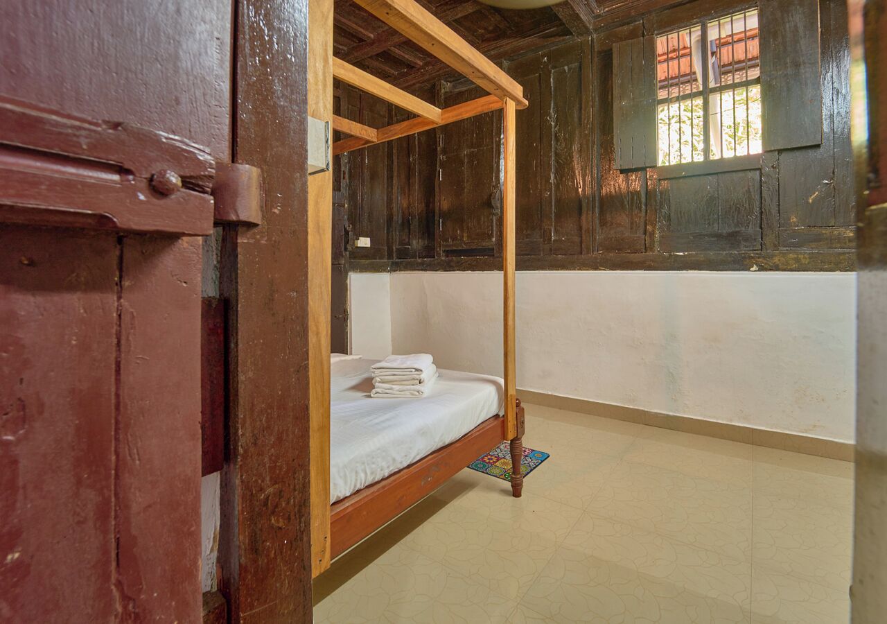 A room with a wooden bunk bed, a small rug, and a window with bars.